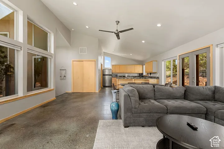 Open-concept living space featuring vaulted ceilings, recessed lighting, expansive windows, concrete flooring, and a ceiling fan