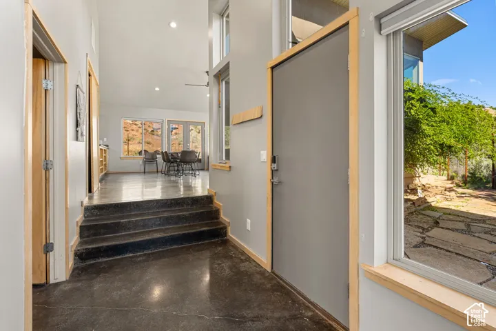 Polished concrete flooring, recessed lighting, wood-trimmed windows, and a modern entry door