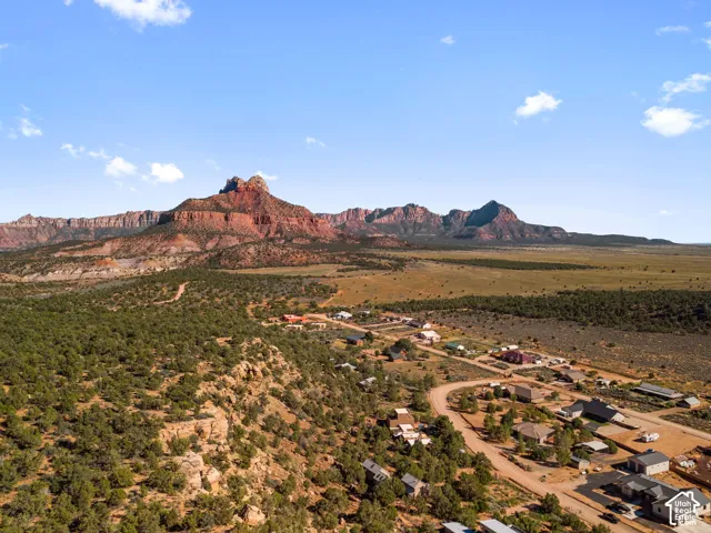 Expansive desert landscape with a residential community, mountainous backdrop, and natural rock formations