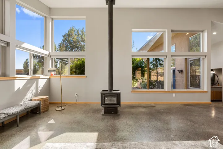 Expansive window arrangement, freestanding fireplace, light-toned walls, wood window sills, and polished concrete flooring