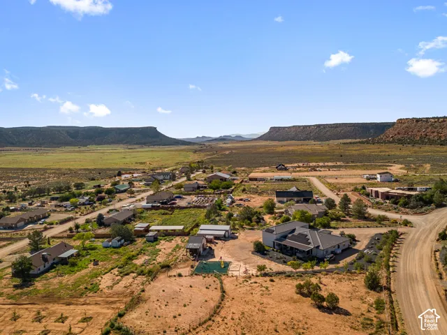 Expansive rural landscape with scattered residential properties, rugged natural terrain, and distant mesa formations