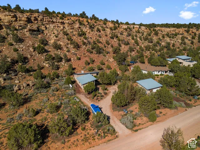 Multiple detached structures situated on a rugged hillside with natural rock formations and abundant natural vegetation