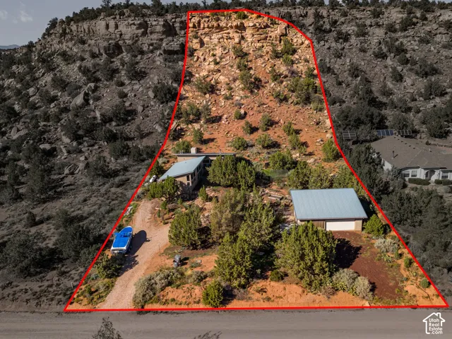 Expansive property featuring a sloped terrain, natural rock formations, and mature desert vegetation
