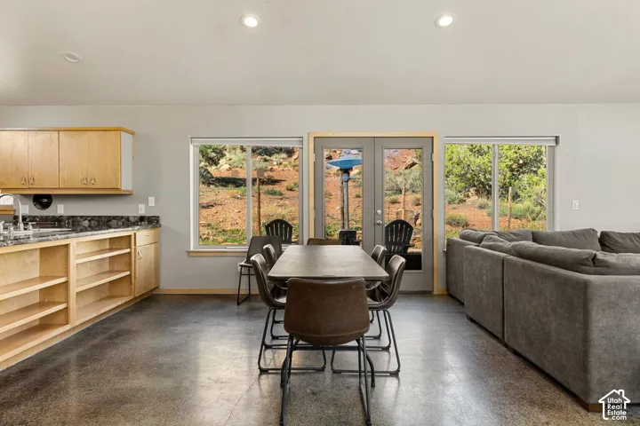 Polished concrete flooring, recessed lighting, and light wood cabinetry with dark countertops