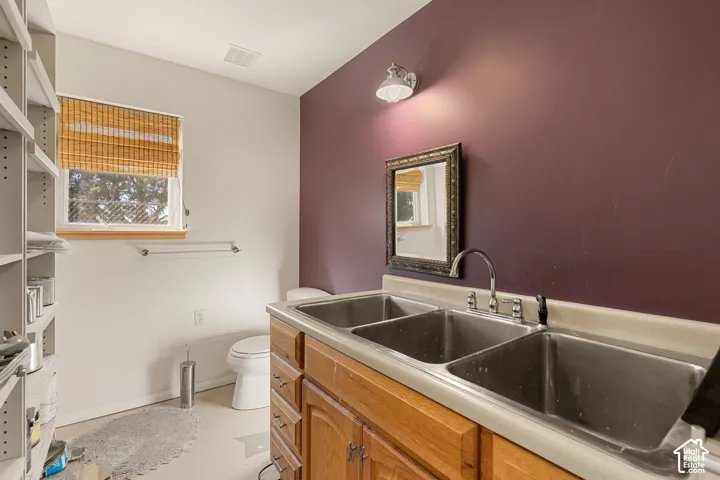 Bathroom in garage with built-in cabinetry with a triple stainless steel sink and chrome faucet