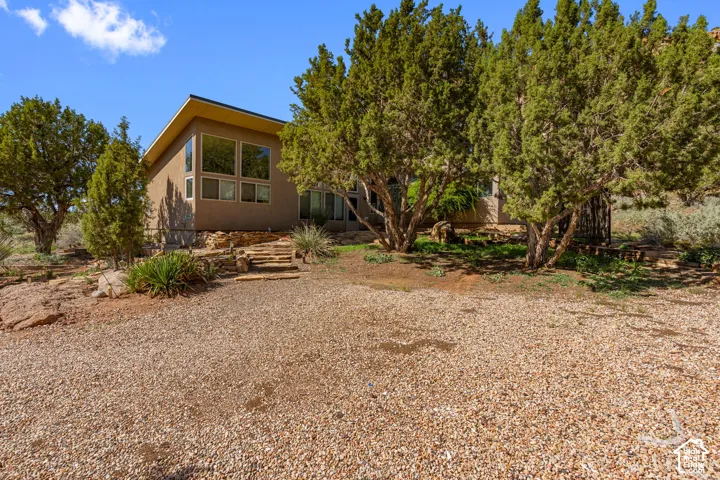 Contemporary exterior with expansive window walls, a gravel drive, natural stone landscaping, and mature trees