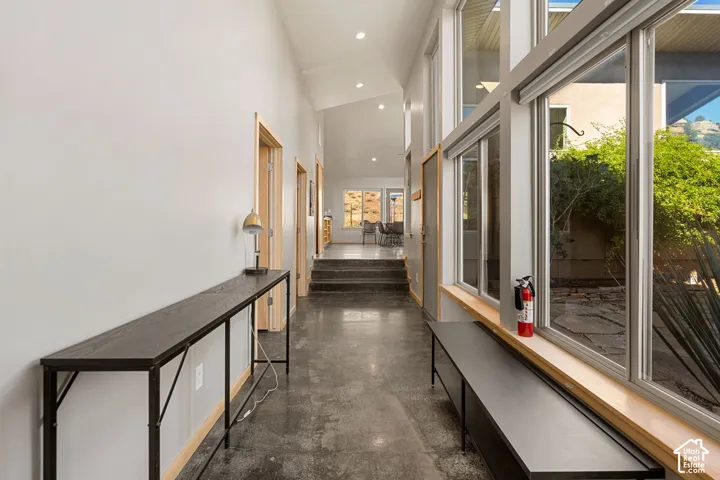 Polished concrete flooring, high vaulted ceilings, recessed lighting, natural wood trim doorways, and expansive windows