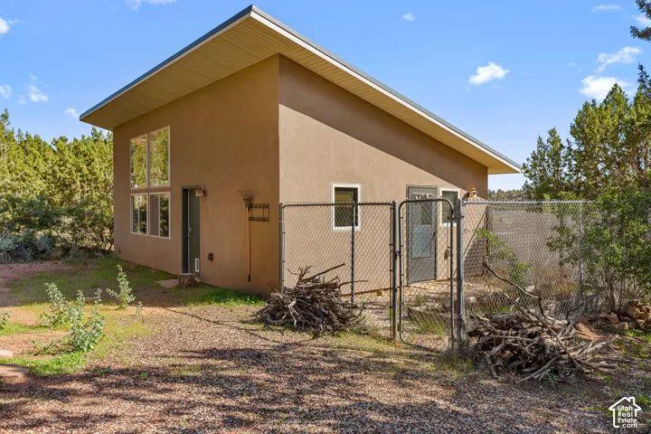 Stucco exterior with a sloped roofline, dual-pane windows, and an enclosed chain-link fence