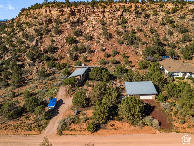 Property set into a rocky hillside with multiple structures, including a detached garage with a metal roof