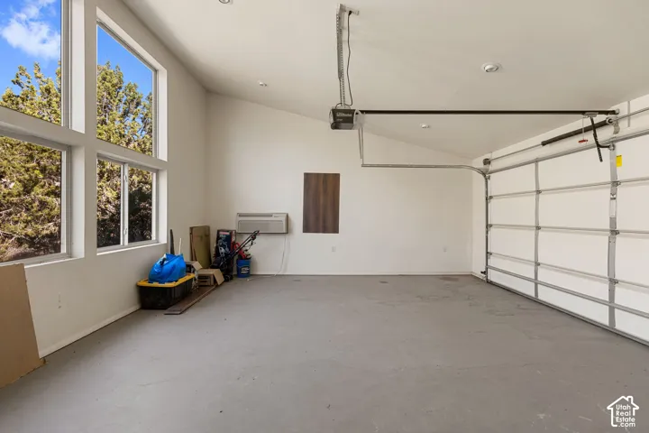 Spacious garage featuring a concrete floor, high ceilings, large multi-pane windows, and a roll-up garage door