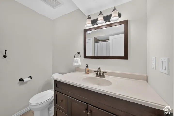 Vanity with integrated sink and dark wood-finish cabinetry, framed mirror, and three-light fixture