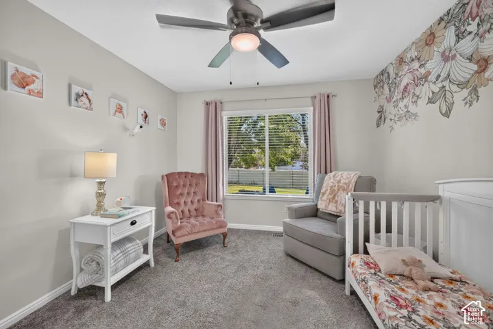 Wall-mounted floral mural accent, window with horizontal blinds, ceiling fan with integrated lighting, and wall-to-wall carpeting