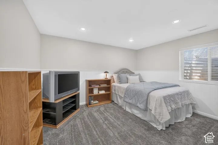 Recessed lighting, window with blinds, upholstered headboard, wainscoting, and carpet flooring