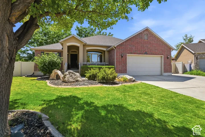 Brick and stucco exterior with an arched entry, prominent bay window, attached garage, and a lush lawn