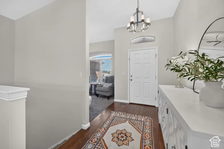 Front entry with rich wood-finish flooring, a white paneled door, and an arched transom window