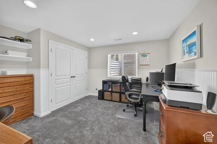 Recessed lighting, grey carpet, built-in shelving, white paneled double doors, and window with blinds