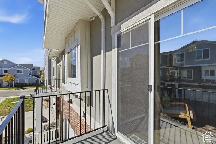 Private balcony with black metal railings, a sliding glass door, and an exterior light fixture