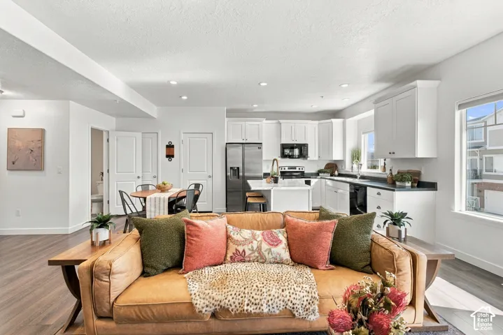 Open-concept living space featuring wood-finish flooring, recessed lighting, and large windows