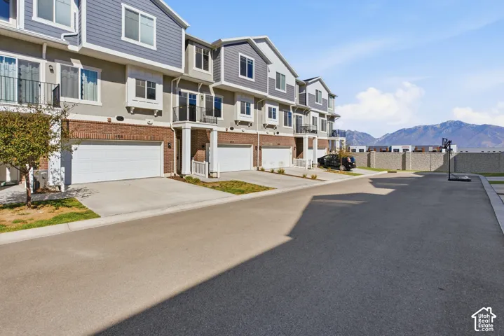 Townhome exterior featuring brick and siding accents, private balconies, and attached garages with paved driveways