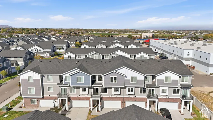 Townhome complex featuring two-car garages, brick and siding exterior, balconies, and a clear mountain backdrop
