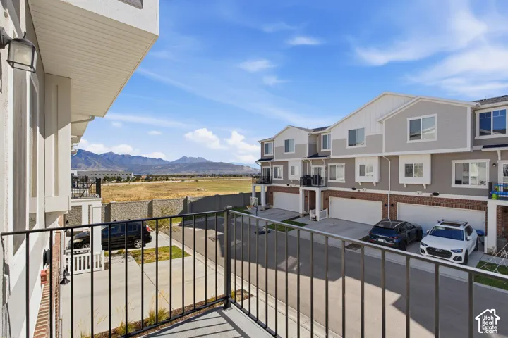Balcony with metal railing, mountain scenery, concrete privacy wall, and multi-level townhome architecture with integrated garages