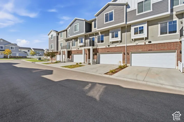 Multi-story townhome with brick and siding exterior, individual garages, and integrated balconies