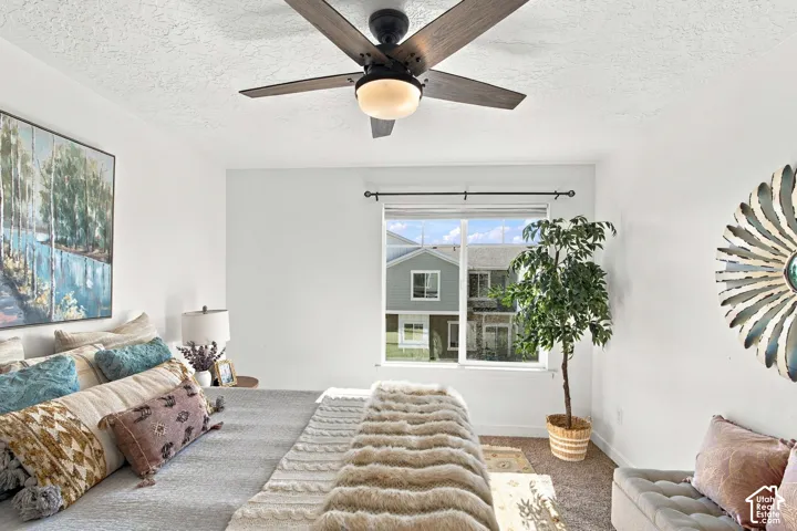White walls with a textured ceiling and a wood-finish ceiling fan