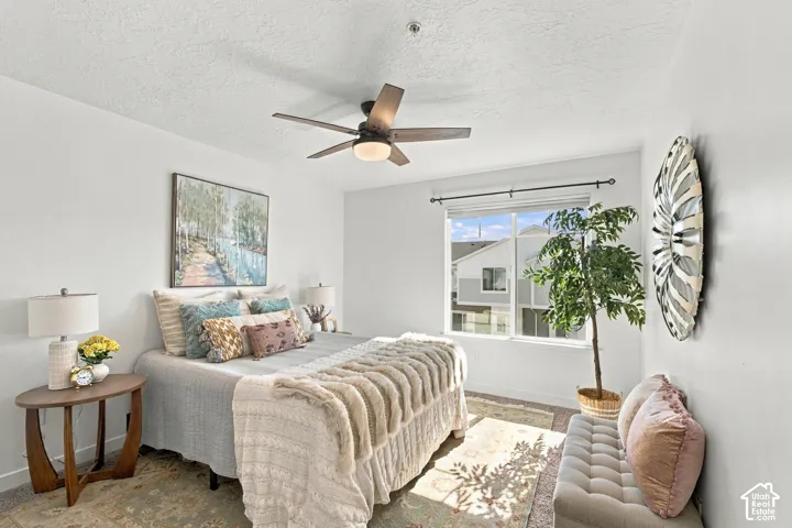 White painted walls, a large window with white trim, dark-finish ceiling fan with integrated lighting, and carpeted flooring
