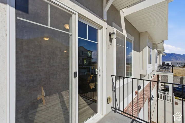 Sliding glass door access to an exterior balcony with black metal railings, a stucco exterior, and multi-pane windows