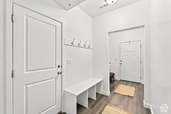 Entryway featuring wood-finish flooring, white paneled doors, a built-in bench, and wall-mounted coat hooks