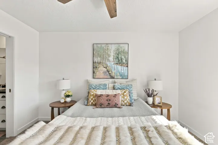 Bright bedroom with white walls, wood-finish ceiling fan, and recessed lighting