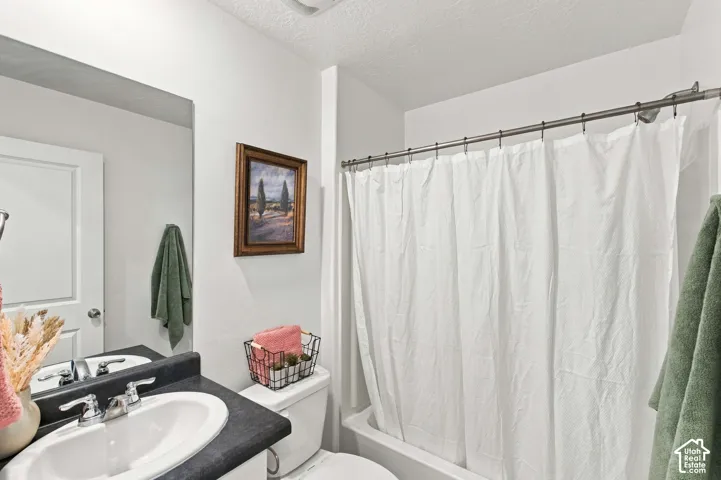 Vanity with an integrated sink and chrome faucet, large wall mirror, and a full-size bathtub with a shower rod