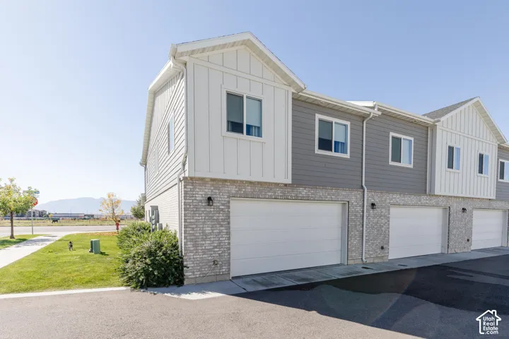Modern townhome exterior featuring vertical and horizontal siding, light brick accents, and individual garage doors