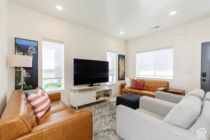 Recessed lighting, multiple windows with roller shades, and a built-in media console