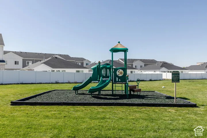 Recreational area featuring a green playset with slides, a rubber mulch safety surface, and a surrounding lawn