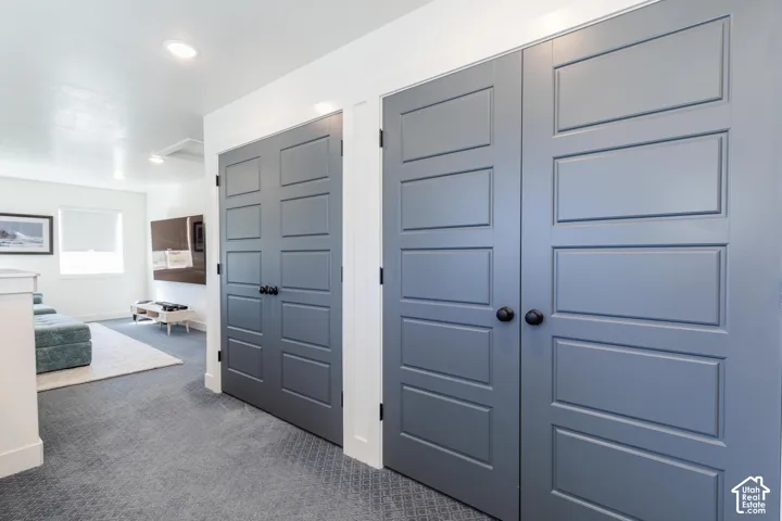 Recessed lighting, white walls, gray panel doors, black hardware, and patterned carpet