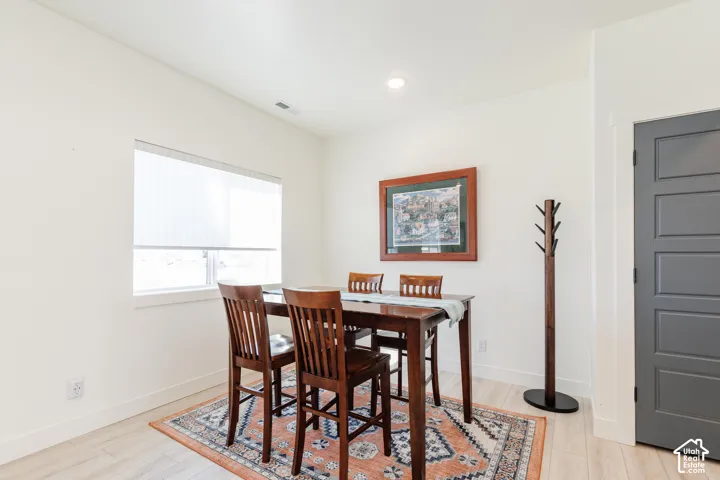 Recessed lighting, light wood-finish flooring, white walls, and a five-panel interior door