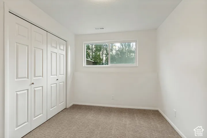 Recessed window, neutral wall paint, bi-fold closet doors, and carpet flooring