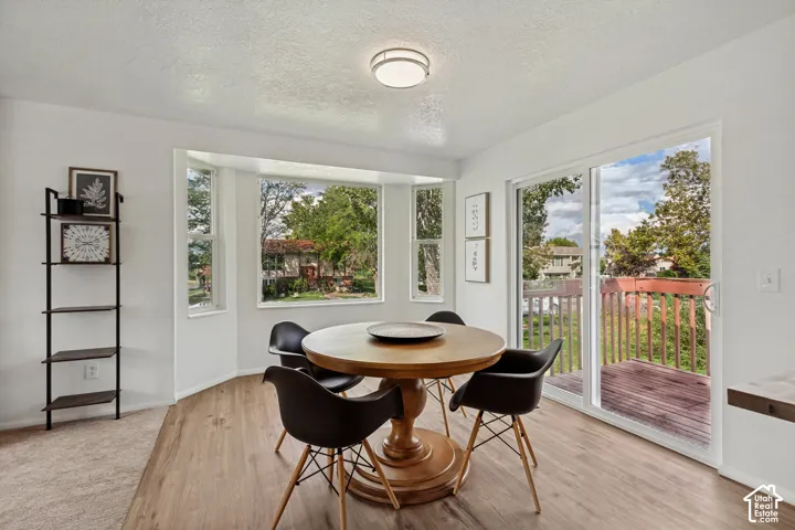Recessed bay window, wood-finish flooring, sliding glass door, white walls, and a built-in light fixture