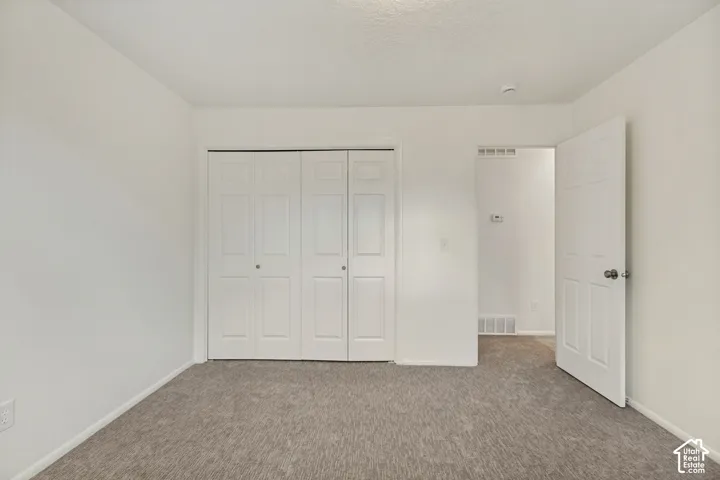 Neutral tone wall paint, textured carpeting, bi-fold closet doors, and a six-panel door with a round knob