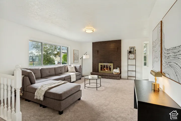 Expansive living space featuring a brick fireplace, large picture windows, and neutral carpeting