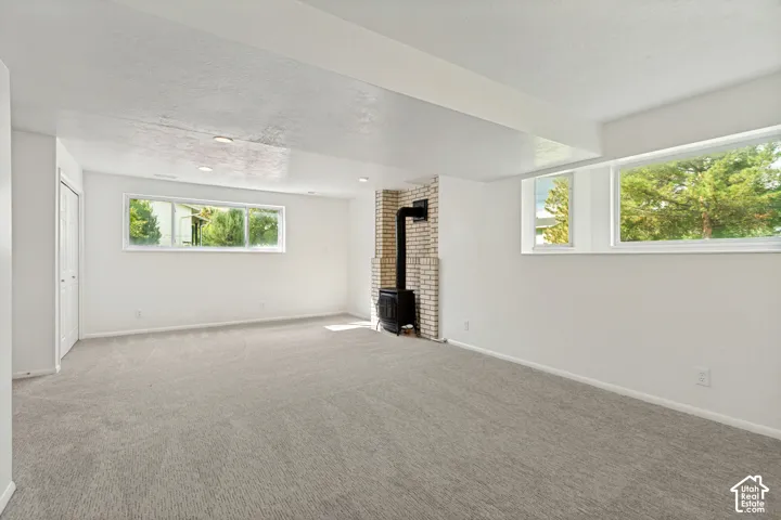 Recessed lighting illuminates a spacious room featuring light-toned carpeting and white walls