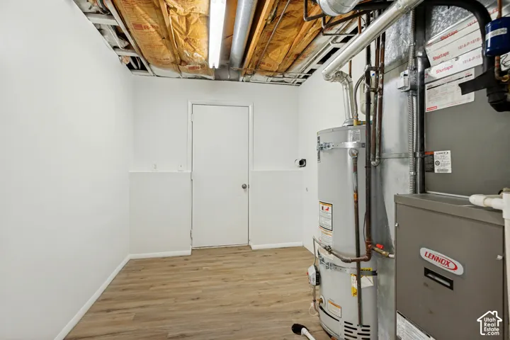 Wood-finish flooring with white baseboards, white walls with wainscoting, and a white door with a round doorknob