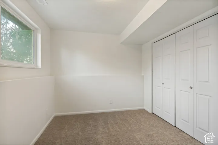 Neutral tone wall finish, textured carpeting, contemporary window, bi-fold closet doors, and recessed lighting