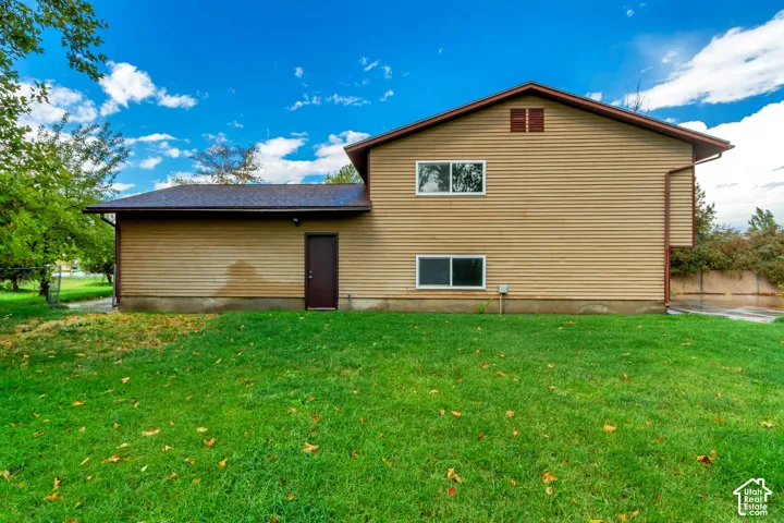 Tan siding exterior with multiple windows and a brown entry door