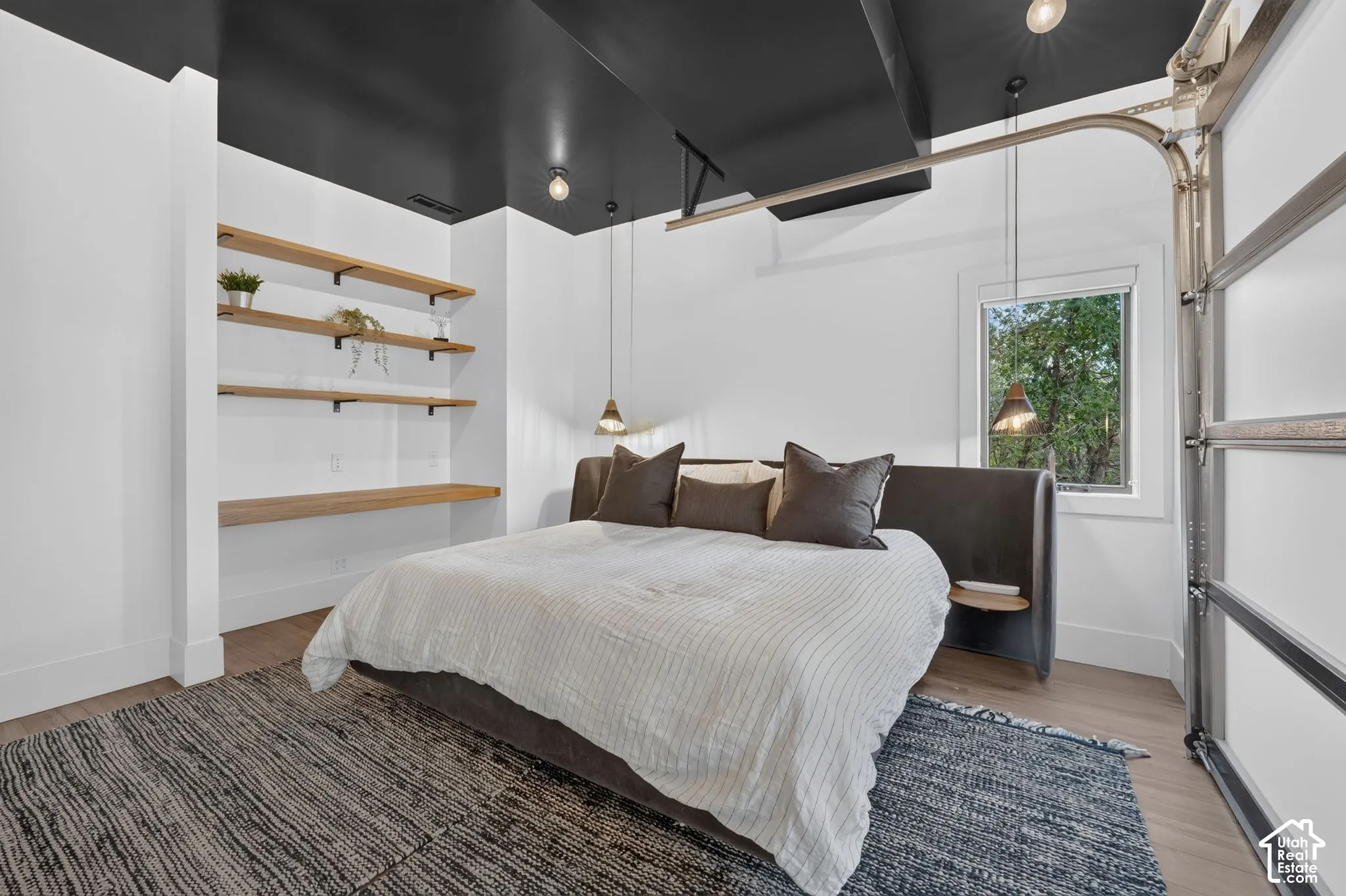 Hardwood-finish flooring, built-in shelving, pendant lighting, and a window with exterior scenery