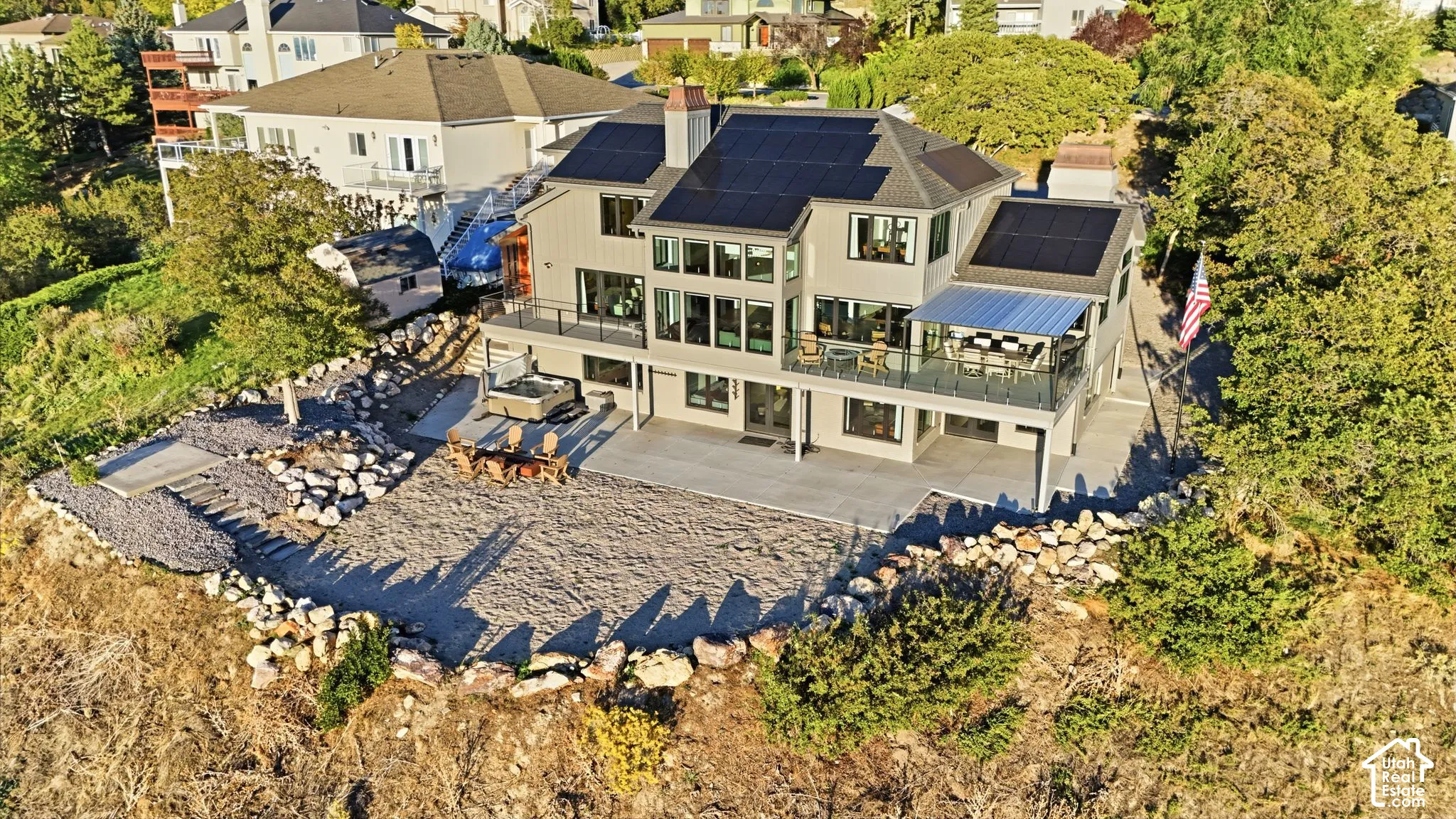 Multi-level residence featuring a rooftop solar array, expansive lower-level patio, and a covered upper-level balcony with glass railings