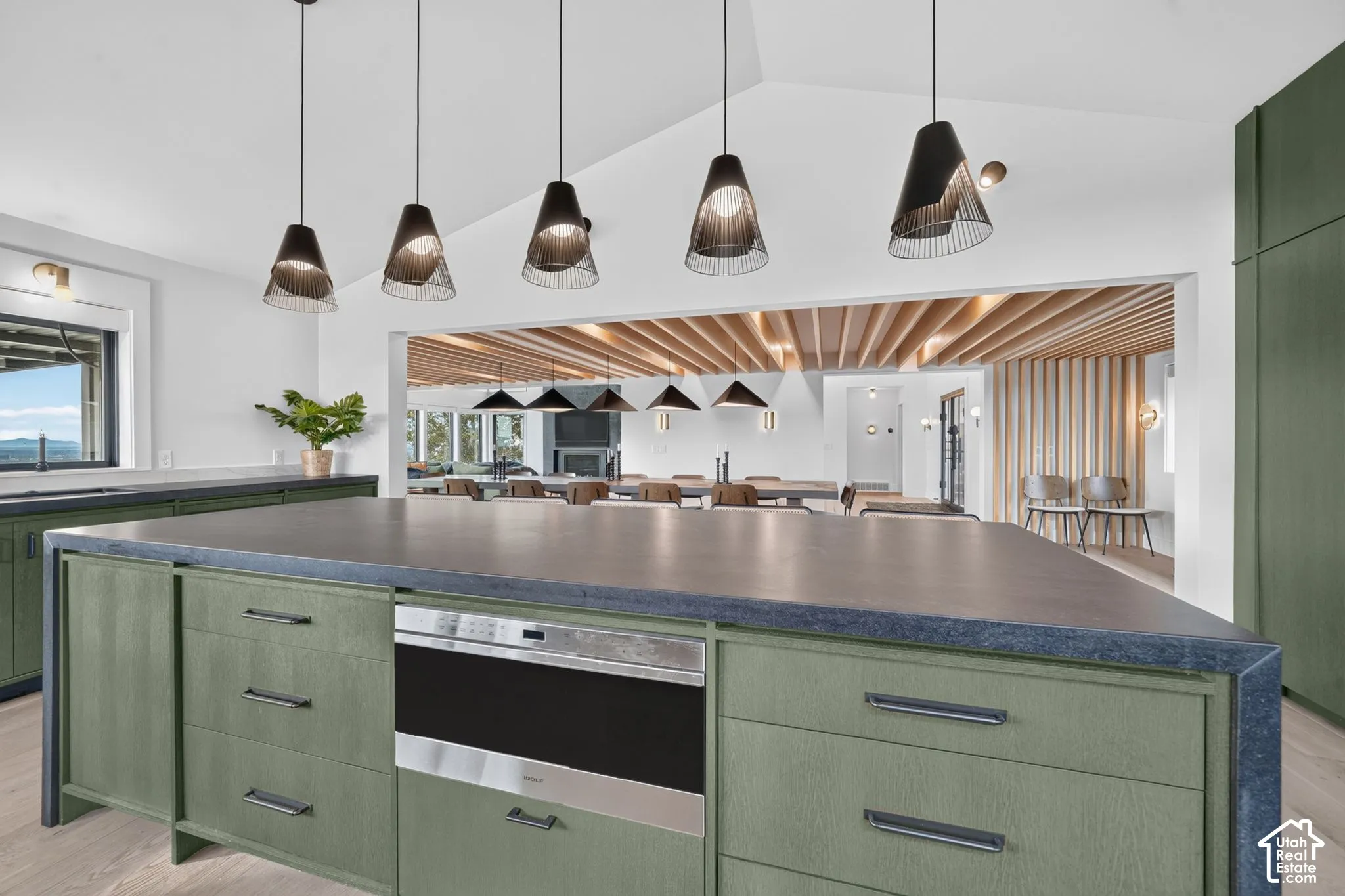 Kitchen featuring a large island with integrated microwave, dark countertops, and sage green cabinetry