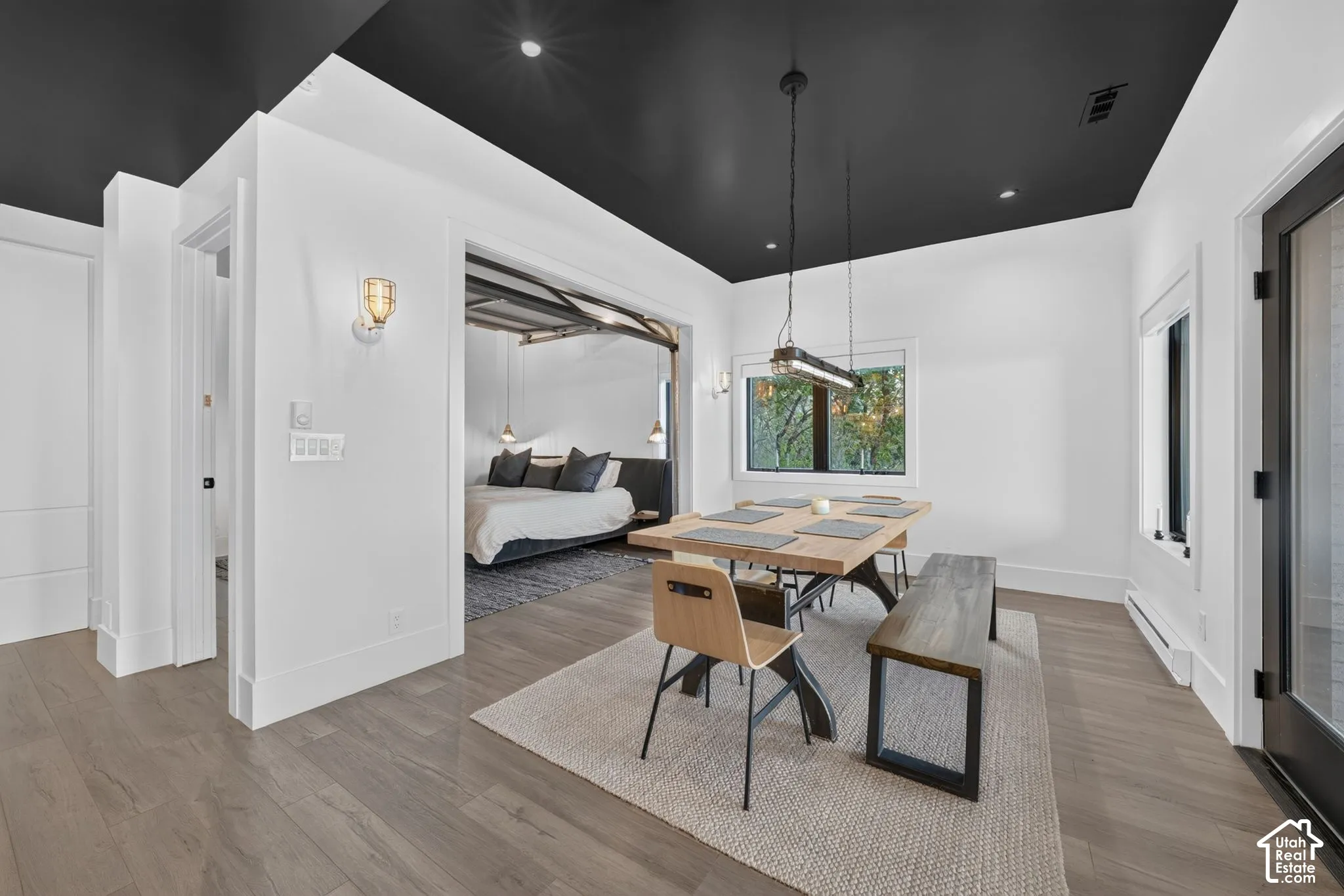 Open concept dining area with light wood-finish flooring, recessed lighting, and a modern linear pendant fixture