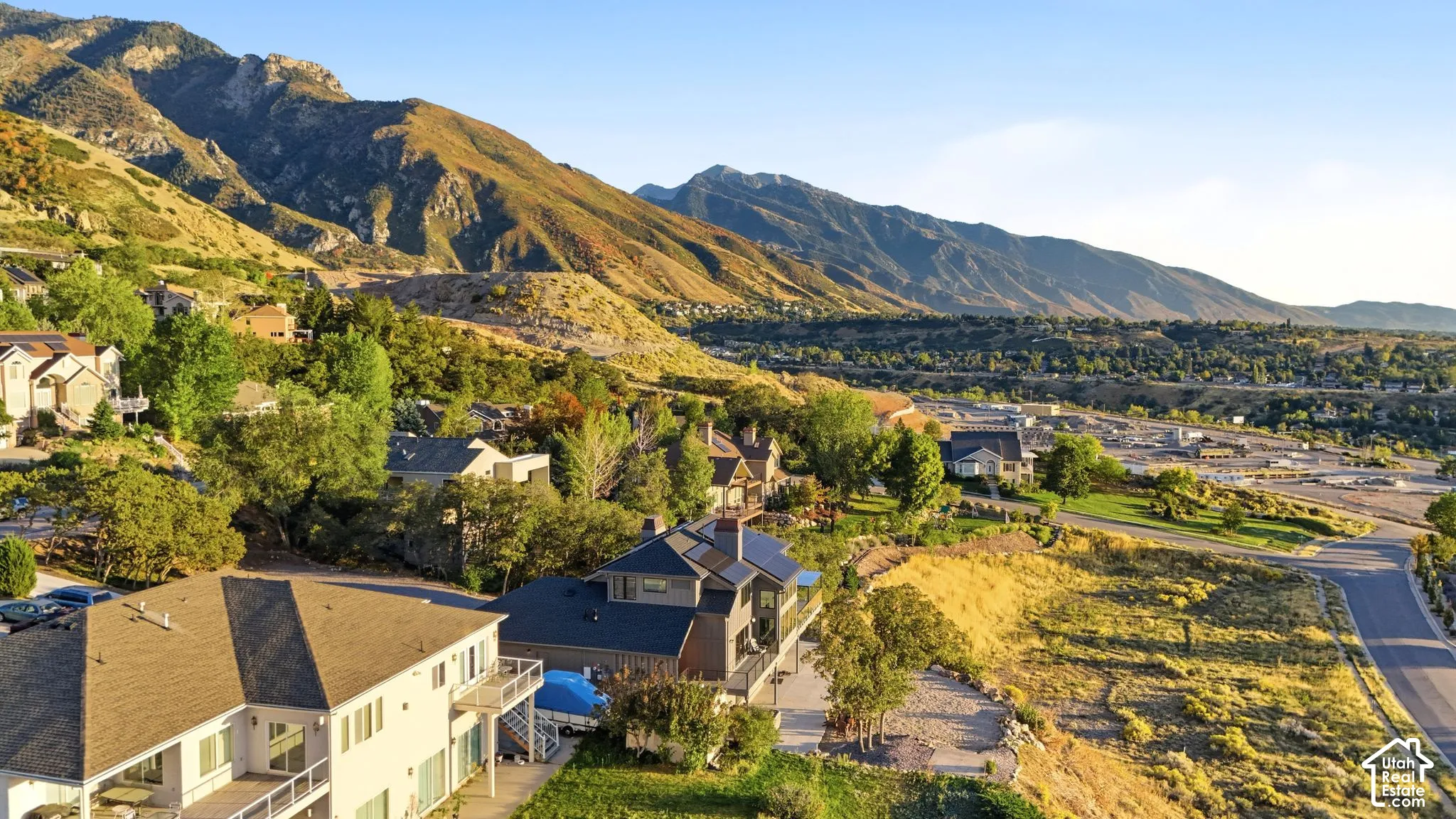 Mountainous terrain, residential properties, paved roads, distant urban development, green landscaping
